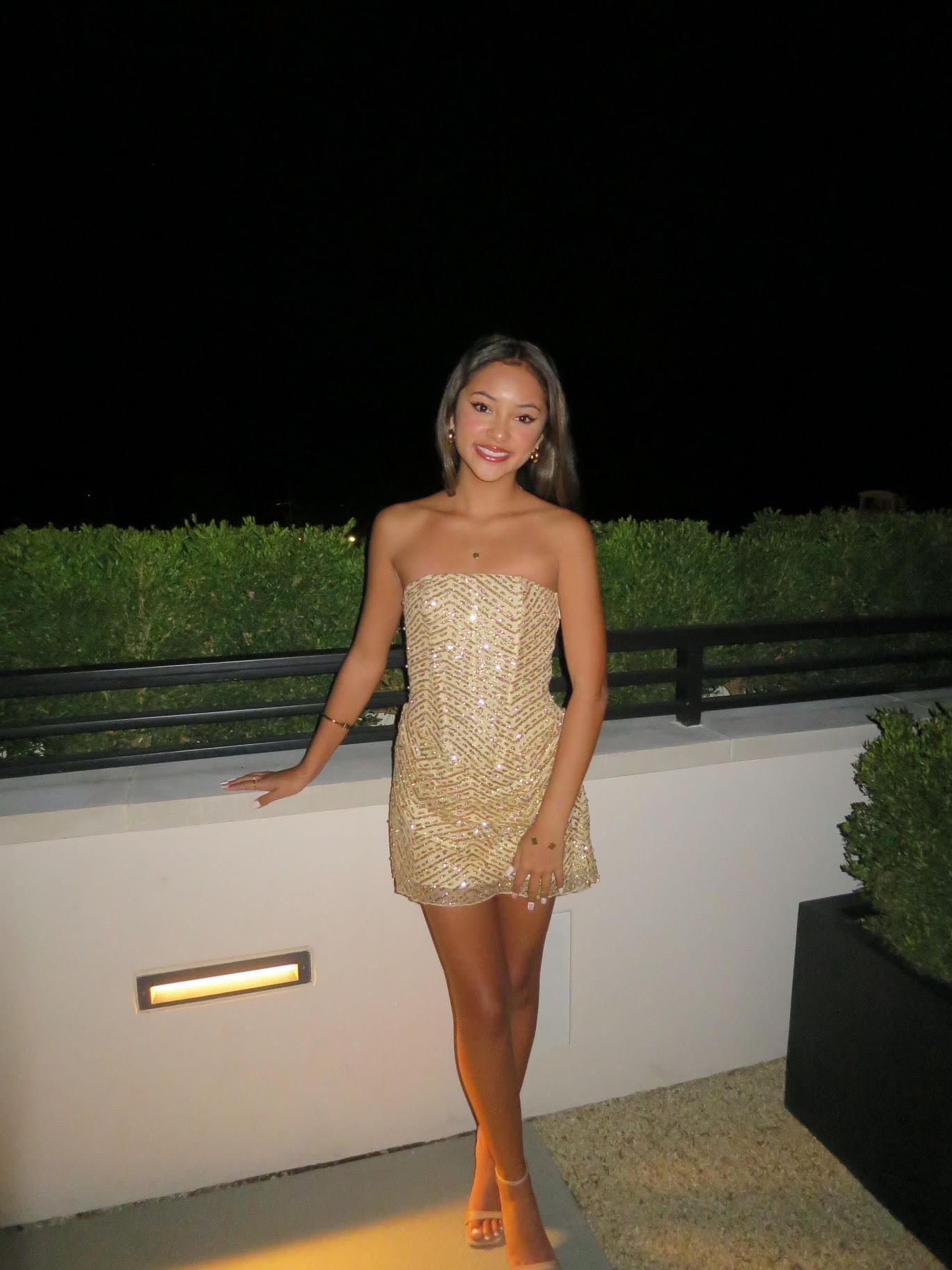 Amanda posing in front of a white wall in formal attire